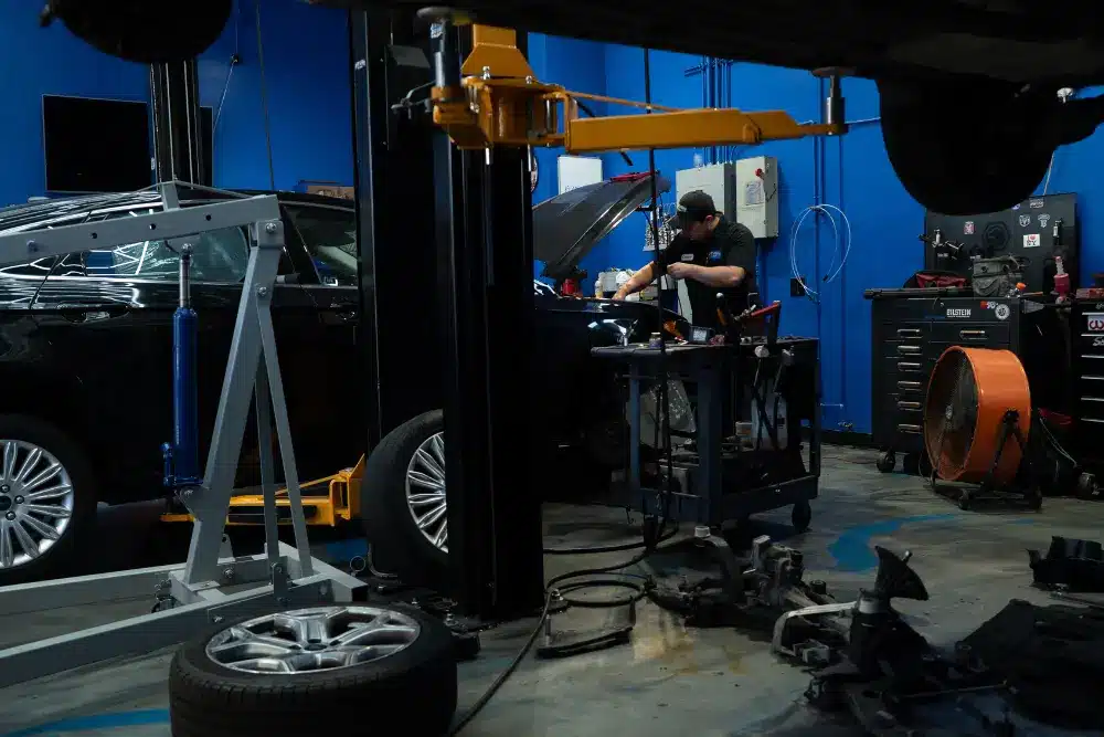 Back-to-school car care, auto repair in Ranch Santa Margarita, CA by Bobby Grich Auto Repair. Image of a technician working under the hood of a vehicle in a modern shop, highlighting the shop’s dedication to precise service, vehicle safety, and reliable performance.