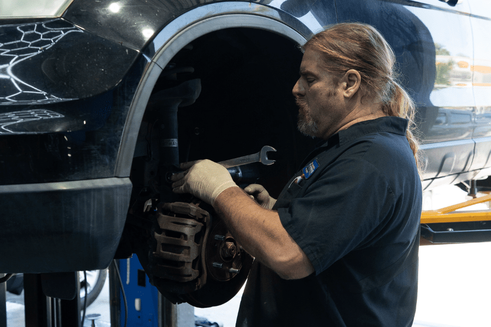 Brake repair in Rancho Santa Margarita, CA by Bobby Grich Auto Repair. Image of a skilled mechanic using a wrench to service the brake system on a lifted vehicle, showcasing professional care and commitment to vehicle safety and performance.