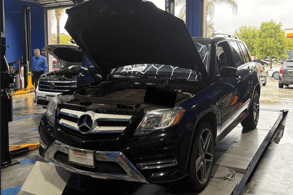 Pre-trip inspection, auto repair in Rancho Santa Margarita, CA by Bobby Grich Auto Repair. Image of a black Mercedes-Benz with the hood open on a lift, indicating routine maintenance or inspection, showcasing the use of advanced equipment for vehicle care.