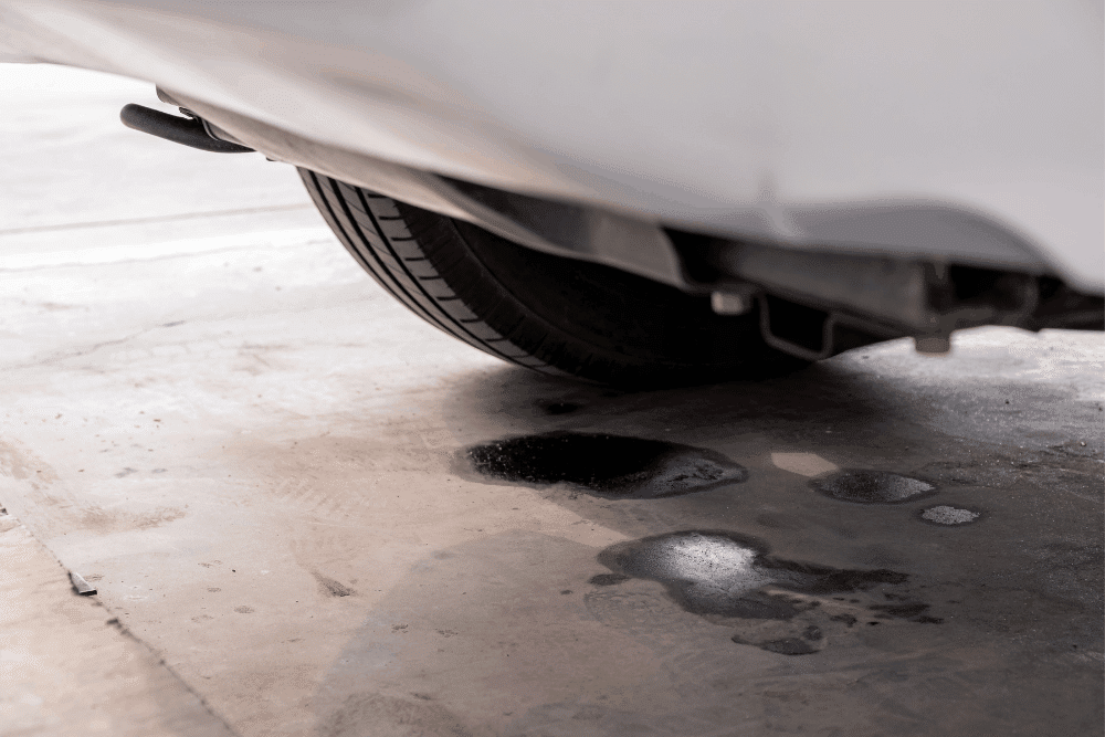 Car fluid leak, auto repair in Orange, CA at Bobby Grich Auto Repair of Orange. Image of dark fluid spots beneath a parked vehicle, highlighting the need for diagnosis to help prevent damage and maintain reliability.