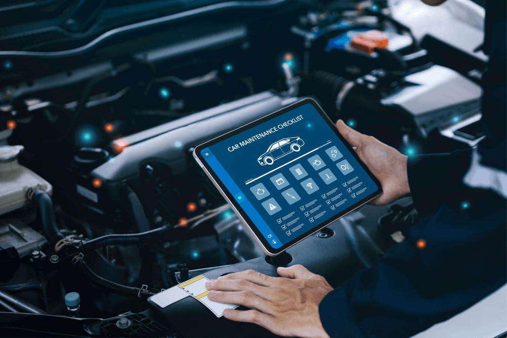 Digital vehicle inspection, auto repair in RSM, CA at Bobby Grich Auto Repair of RSM. Image of a technician using a digital maintenance checklist on a tablet beside an open engine bay to support reliable vehicle service.