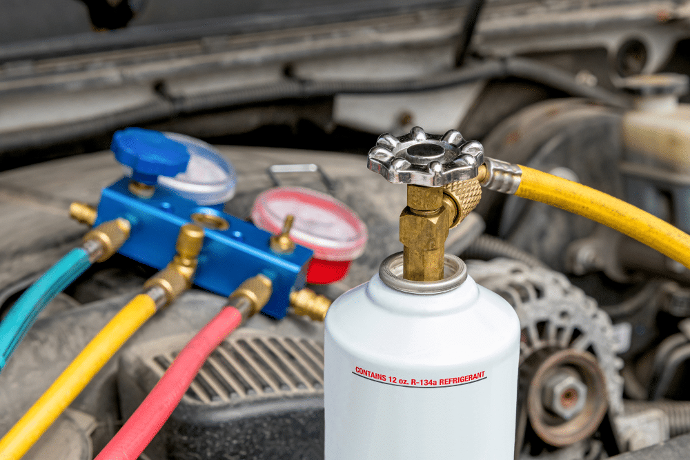 Car a/c service, auto repair in Murrieta, CA at Bobby Grich Auto Repair of Temecula. Image of R-134a refrigerant and manifold gauges connected in an engine bay for air conditioning maintenance.